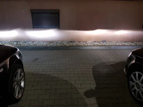 Jasne światła z przodu Audi A4 B6 oświetlają ścianę.
