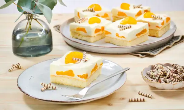 Saftiger Mandarinen Schmand Kuchen Blech, dekoriert mit Mandarinenstücken und Schokoröllchen. Ein Genuss für Augen und Gaumen!