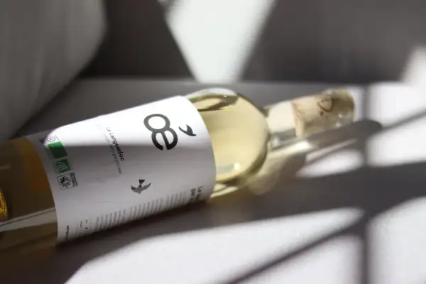 Flasche mit hellem Wein, Etikett mit "8" und Vögeln, Bio-Siegel. Ein Wein ohne Sulfite, der die Natur ehrt.