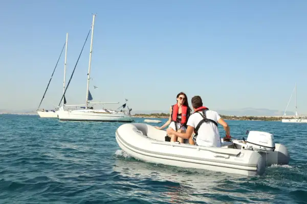 Coppia su una tender barca, con vele bianche all'orizzonte.
