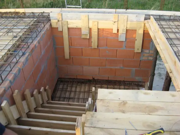 Budowa schodów drewnianych: szalunek z desek i cegieł, zbrojenie pod beton.
