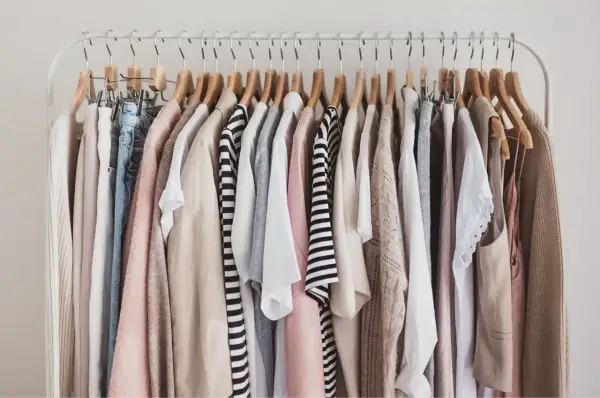 Kleiderständer mit einer Auswahl an Kleidungsstücken in neutralen Farben, die sich gut für eine Capsule Wardrobe eignen.