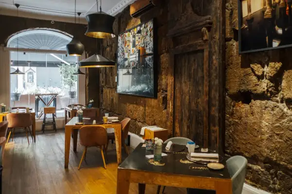 Interno di un ristorante con tavoli apparecchiati e pareti in pietra grezza. Un'atmosfera che fa pensare ai migliori ristoranti di Palermo.