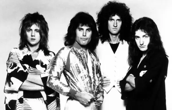 Czterech członków zespołu Queen, Freddie Mercury, Brian May, Roger Taylor i John Deacon, pozuje do zdjęcia. To oni tworzą zespół Queen, który nagrał największe hity.