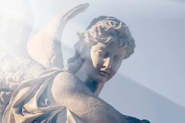 Kamienna rzeźba anioła, z promieniem światła padającym na twarz. W ciszy serca rodzi się modlitwa do anioła stróża o pomoc.