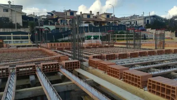 Cantiere edile con mattoni e armature in vista. Si sta preparando il miglior isolante termico per soffitto, con blocchi di laterizio pronti per la posa.