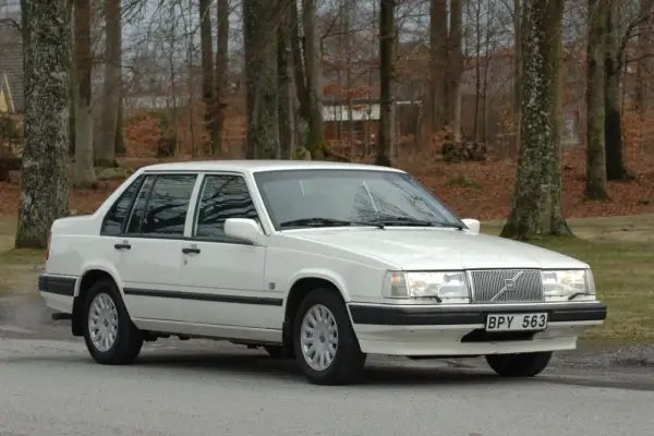 Vit Volvo 940 classic parkerad vid en skogsväg. Bilen är i fint skick med blank lack och kromade detaljer.