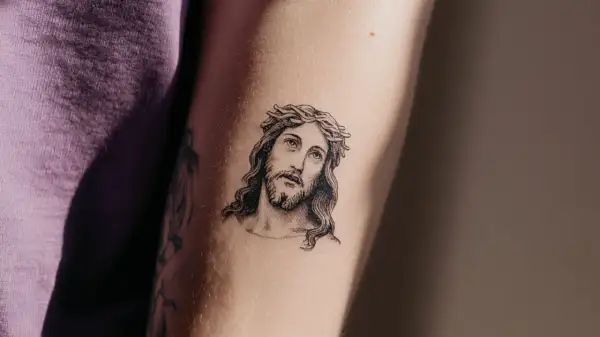 Ein Porträt von Jesus mit Dornenkrone, ein Beispiel für minimalistische Tattoos, auf einem Arm.