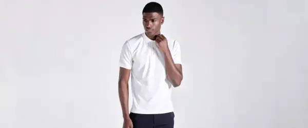 Ein Mann in einem weißen Poloshirt, das klassische Merkmale wie den Kragen und die Knopfleiste zeigt.