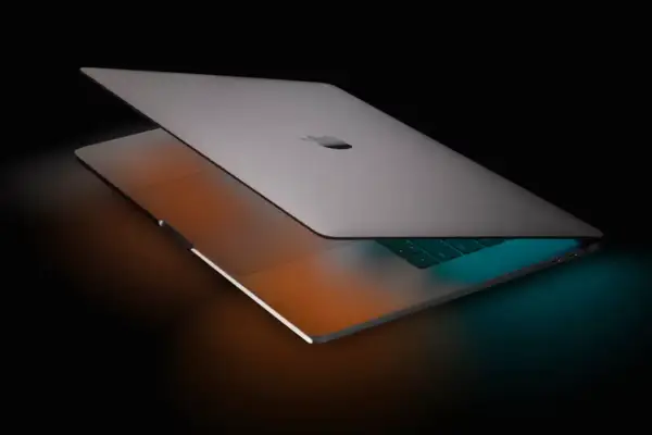 Elegancki MacBook Pro 16 z podświetlaną klawiaturą, otoczony ciepłym i chłodnym światłem, gotowy do pracy.