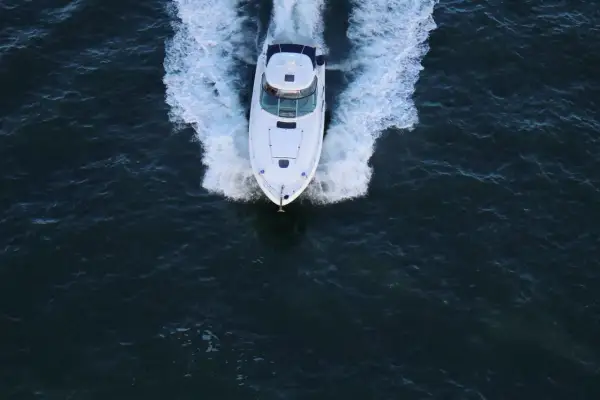 Un bianco yacht naviga veloce, lasciando una scia di spuma. La sua posizione è centrale, in un mare scuro e mosso.