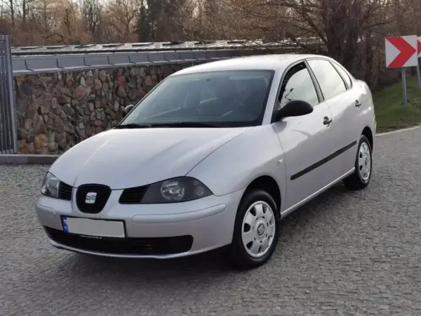 Srebrny Seat Cordoba zaparkowany na brukowanej drodze, z kamiennym murem w tle.