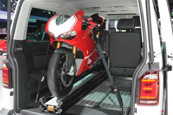 Una moto deportiva roja lista para transportar en furgoneta, asegurada con correas sobre un riel.