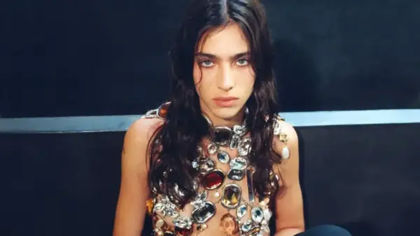 Joven con mirada intensa, adornada con un collar de gemas y perlas que evoca la belleza de una loli bahía.
