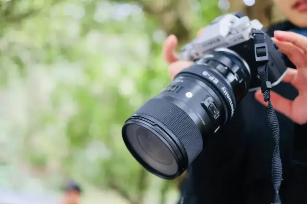 Srebrny aparat fotograficzny dla początkujących z obiektywem Sigma EF-S. Idealny do nauki fotografii.