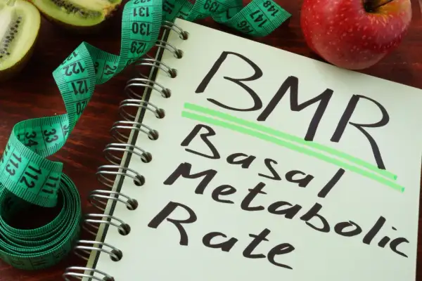 BMR co to? Notatnik z napisem "Basal Metabolic Rate", miarka krawiecka i owoce kiwi oraz jabłko.