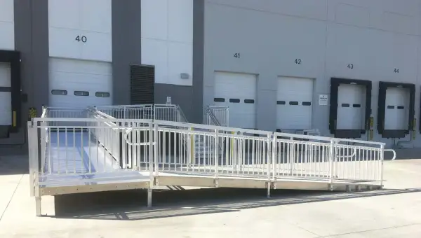 A modular wheelchair ramp system is installed outside a warehouse, providing accessibility to loading docks. This shows how to build a wheelchair ramp for easy access.