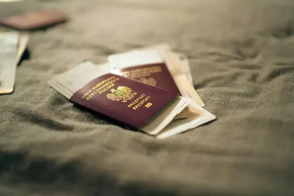 Kilka paszportów leży na szarym materiale. Zastanawiasz się, jak wyrobić paszport? To pierwszy krok do podróży!