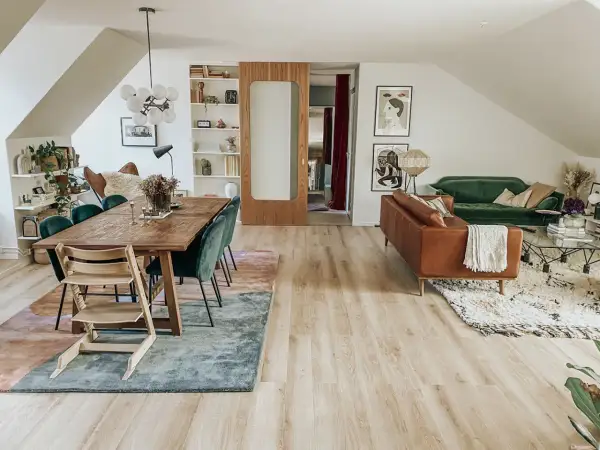 Två mattor i samma rum: en stor, abstrakt matta under matbordet och en mindre, mönstrad matta framför soffan.