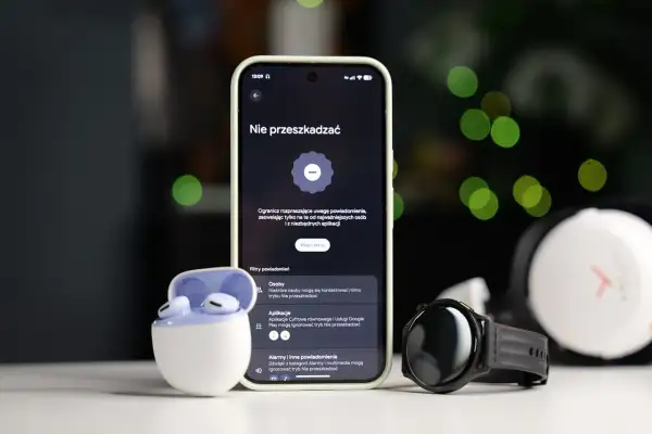 Smartfon z włączonym trybem nie przeszkadzać Samsung, obok słuchawki i smartwatch.