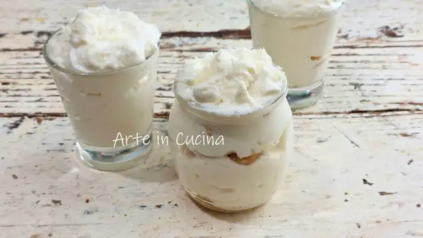 Délicieux tiramisu coco crémeux, servi dans des verrines et un pot en verre, parsemé de copeaux de noix de coco.