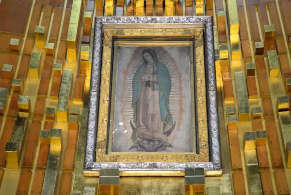 Obraz Matki Boskiej z Guadalupe, którego niezwykłe właściwości badała NASA, w złotej ramie na tle drewniano-złotej ściany.