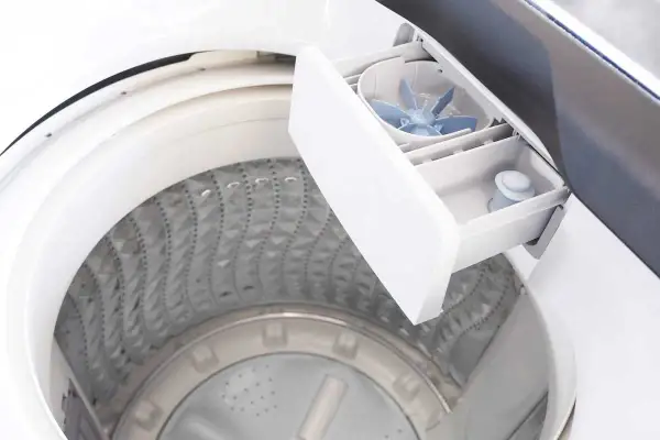 Cassetto detersivo lavatrice aperto, mostra come usare il detersivo liquido. La vaschetta è pronta per il bucato.