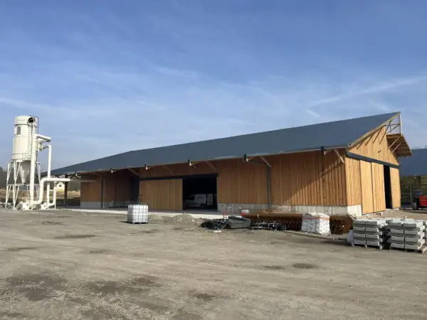 Nouveau bâtiment en bois, prêt à accueillir un atelier de menuiserie bois. Une tour de dépoussiérage est installée à côté.