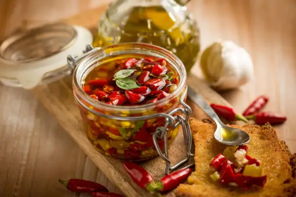 Peperoncino sott'olio con aglio, un tesoro piccante in un barattolo di vetro, pronto per insaporire ogni piatto.