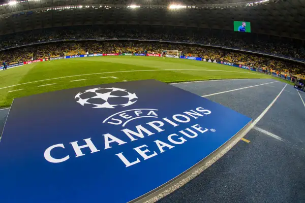 Logo Ligi Mistrzów UEFA na tle stadionu piłkarskiego.