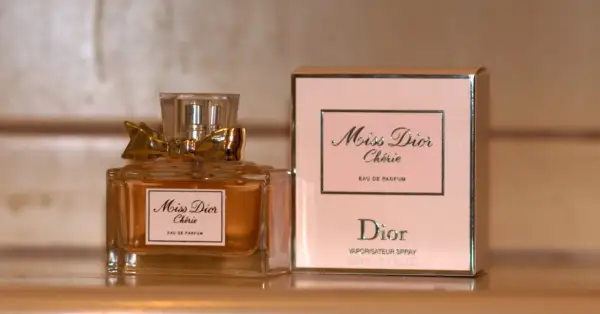 Elegancka butelka i pudełko perfum Miss Dior Chérie, ozdobione złotą kokardką, emanują luksusem.