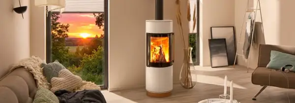 Gemütliches Wohnzimmer mit brennendem Kamin, der die Frage aufwirft: darf man im Sommer den Kamin anmachen? Sonnenuntergang draußen.