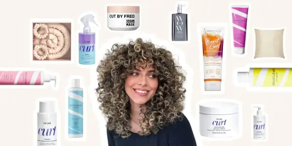 Une femme aux cheveux bouclés naturels rayonne, entourée de produits pour le soin des cheveux bouclés.