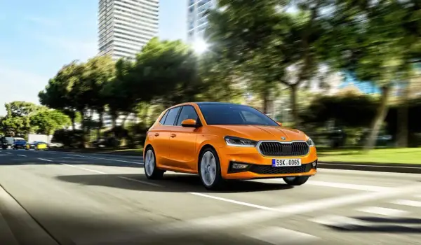 Pomarańczowa Skoda Fabia jedzie po mieście. Idealny samochód, by nauczyć się, co trzeba umieć na pierwszą jazdę.