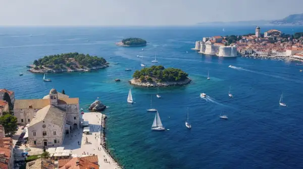 Un día perfecto para tu ruta Croacia 7 días: veleros navegan en aguas turquesas cerca de islas verdes y la histórica ciudad amurallada.