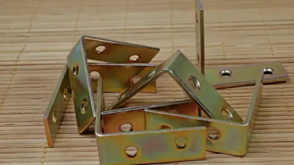 Stos różnych rodzajów kątowników metalowych, gotowych do wzmocnienia konstrukcji.