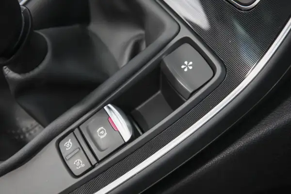Bouton de frein à main électronique et autres commandes dans une voiture. Le frein à main ne serre plus, prix de la réparation à considérer.