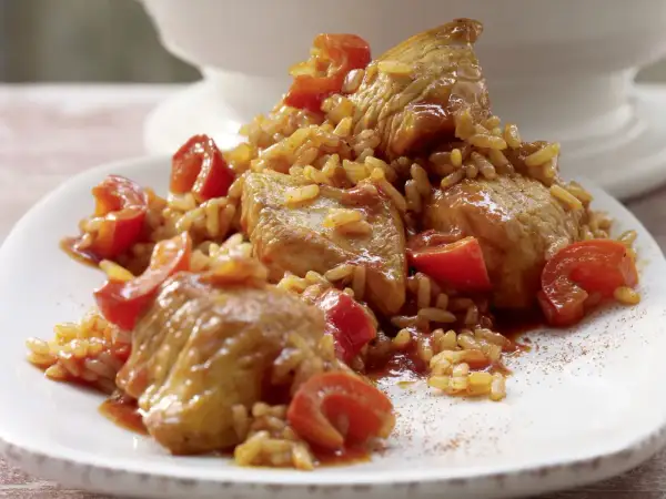 Serbisches Reisfleisch mit zarten Fleischstücken und Tomaten, serviert auf einem weißen Teller.
