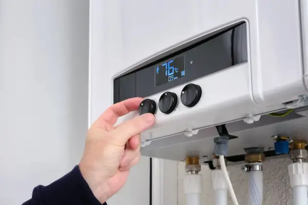 Hand dreht Regler an Heizung. 76°C. Was bedeutet 65 Prozent erneuerbare Energien? Effizienz ist wichtig.