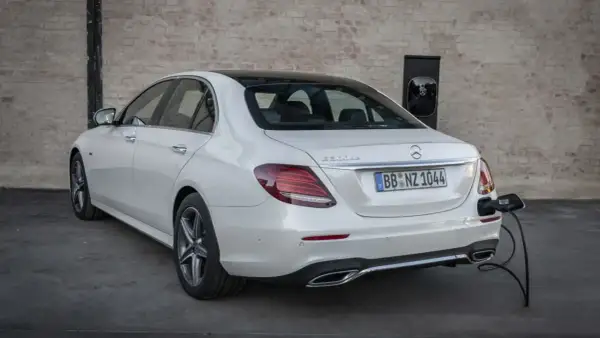 Un Mercedes 300de blanco, con el distintivo "E 300de", está enchufado a un cargador eléctrico.