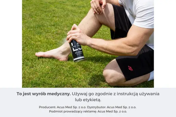 Mężczyzna aplikuje spray przeciwbólowy i przeciwzapalny na nogę siedząc na trawie.