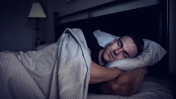 Man sleeping soundly, embracing deep sleep for optimal muscle recovery.