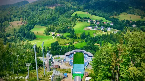 Malownicza panorama Wisły w górach. Widok na skocznię narciarską, wyciągi i zielone wzgórza z domkami.