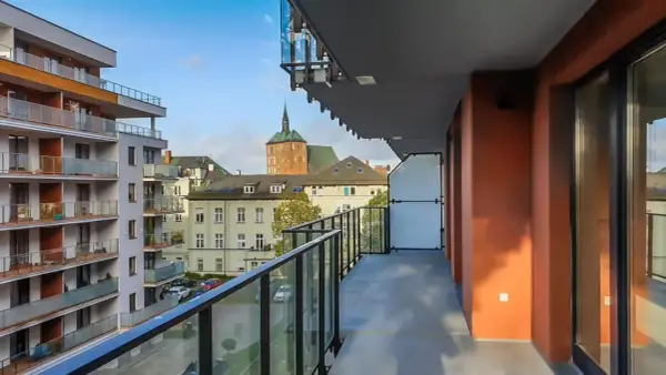 Widok z balkonu na nowoczesne bloki i zabytkowe kamienice w Kołobrzegu. Pilnie sprzedam mieszkanie w tej okolicy!