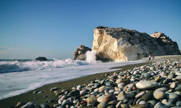 Skała Afrodyty, gdzie fale rozbijają się o brzeg, a kamienista plaża wita spacerowiczów.