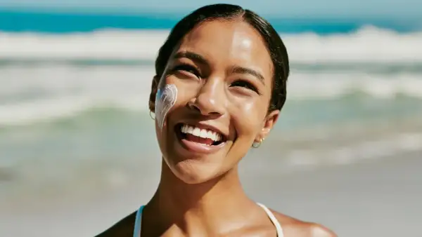 Strahlendes Lächeln am Strand, Sonnencreme schützt vor Hautalterung.