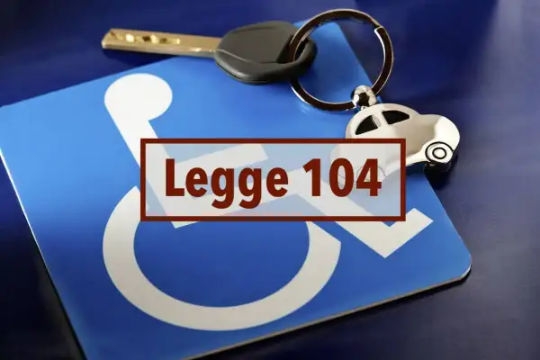 Chiave e portachiavi a forma di auto su un cartello blu con simbolo disabili e testo "Legge 104".