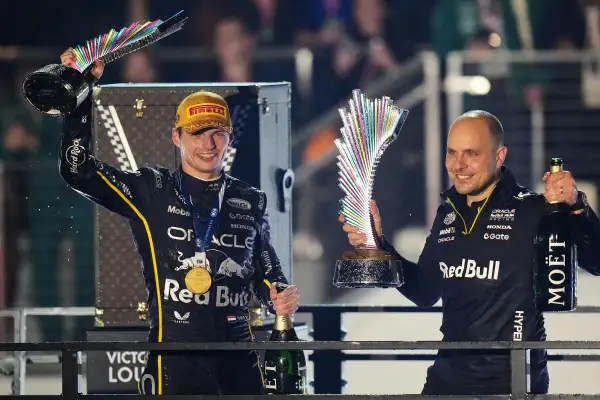 Max Verstappen celebra con un trofeo y champán, junto a Gianpiero Lambiase, tras una victoria.