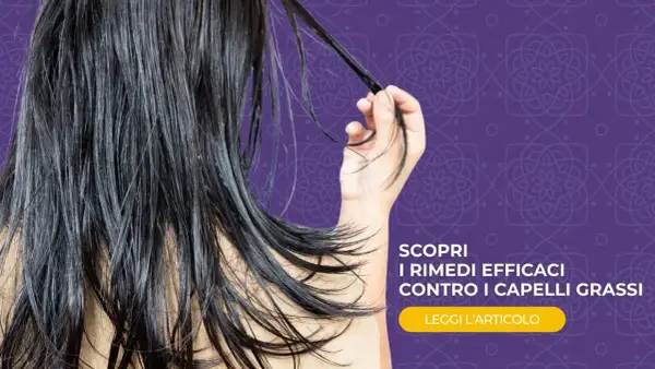Capelli lunghi e scuri, che sembrano un po' appesantiti, con una mano che ne raccoglie una ciocca. Scopri rimedi efficaci contro i capelli grassi.