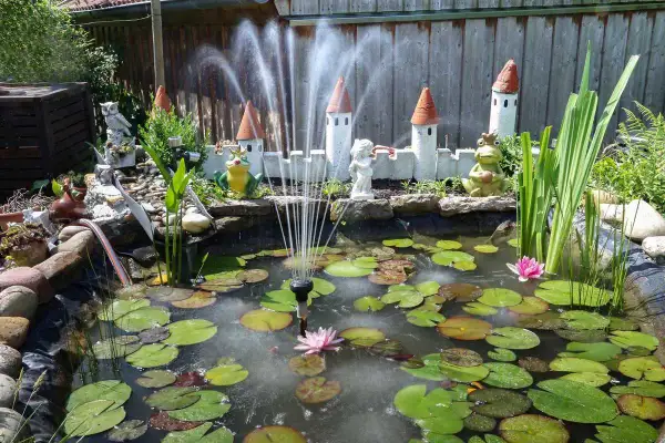 Un bassin avec nénuphars, fontaine et décorations de château. Idéal pour fabriquer cache filtre bassin.